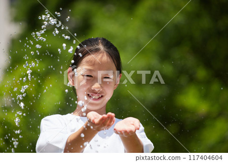 Elementary school girls having fun playing in water at a park during summer vacation Elementary school girls having fun playing in water at a park during summer vacation 117404604