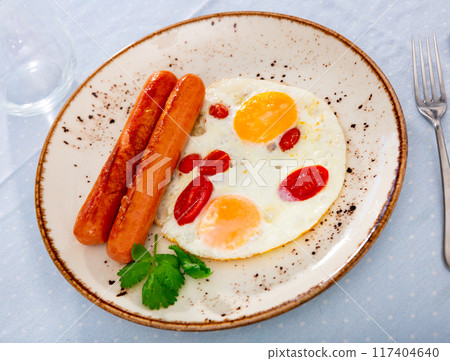 Fried eggs with tomato served with sausage 117404640