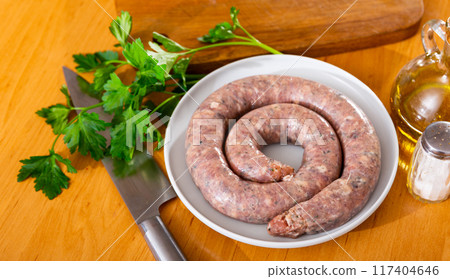Coil of raw butifarra on plate with knife and condiments Coil of raw butifarra on plate with knife and condiments 117404646