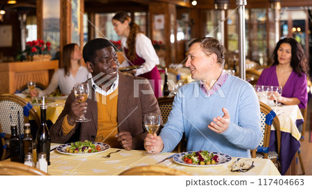 Meeting of two cheerful friends at dinner in restaurant Meeting of two cheerful friends at dinner in restaurant 117404663