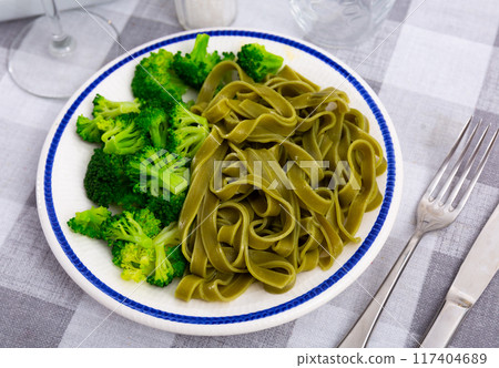 Green pasta with side of broccoli on white plate Green pasta with side of broccoli on white plate 117404689
