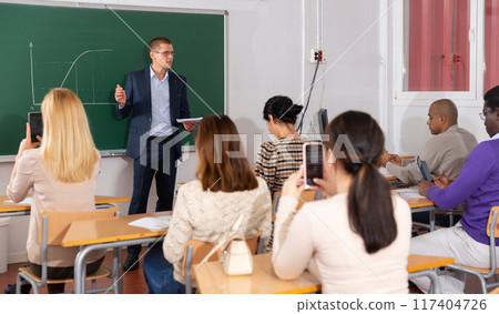 Teacher giving lesson to group of adult students Teacher giving lesson to group of adult students 117404726