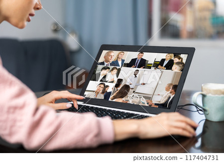 Woman with laptop having video call with co-workers at home 117404731