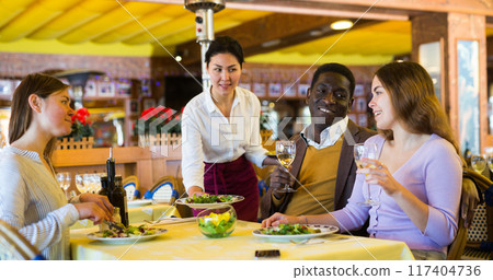 Couple eating in restaurant with their female friend during date Couple eating in restaurant with their female friend during date 117404736