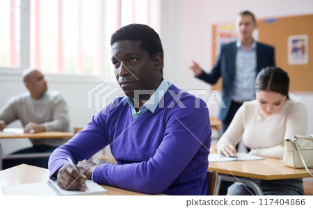 African american man attentively listening lecture in classroom African american man attentively listening lecture in classroom 117404866