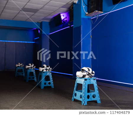 VR headsets and controllers in virtual reality gaming room 117404879