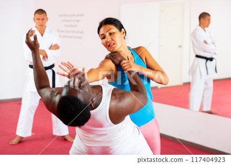 Men and woman training self-protection martial arts in gym Men and woman training self-protection martial arts in gym 117404923
