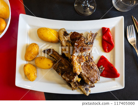 Roasted lamb ribs aragonese, pepper and potato served on plate 117405000