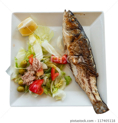 There is plate with fried whole carcass zander fish and mix vegetable salad on table 117405118