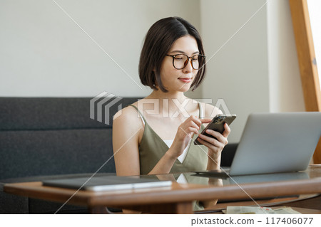 A woman using a smartphone in the living room at home A woman using a smartphone in the living room at home 117406077