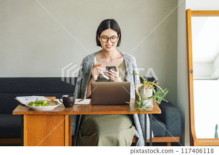 Woman using smartphone at home 117406118