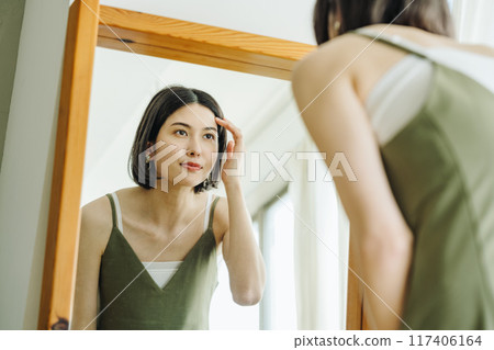 A woman getting ready in the mirror A woman getting ready in the mirror 117406164