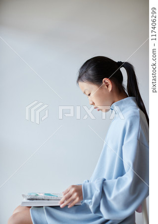 A child in elementary school reading a book in the living room at home 117406299