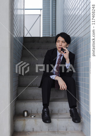 商人在緊急樓梯上抽電子煙 117408248
