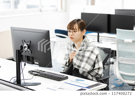 A business woman who is cold because the air conditioner in the office is set at a low temperature 117408272