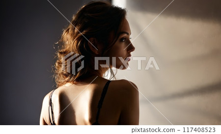Woman in lingerie back view with tasteful detail intimate setting dimmed spotlight secretive allure respectful 117408523
