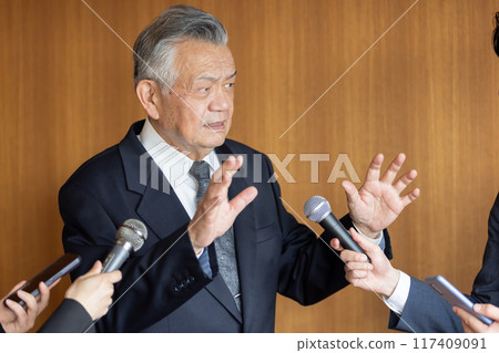 Senior businessman responding to questions from reporters 117409091