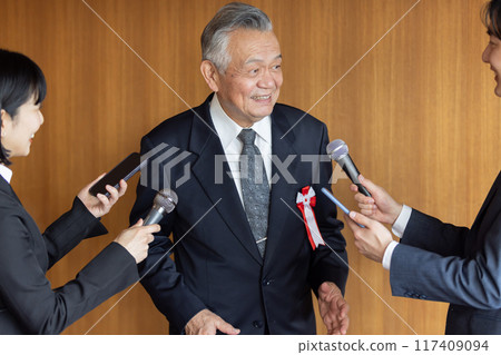 Senior businessman responding to questions from reporters 117409094