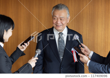 Senior businessman responding to questions from reporters 117409096