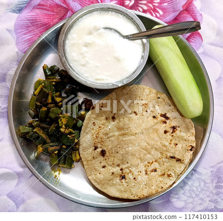 Indian Cuisine Bhindi or okra curry and Roti or chapati with curd served in a plate. selective focus Indian Cuisine Bhindi or okra curry and Roti or chapati with curd served in a plate. selective focus 117410153