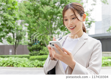 Business woman searching on a smartphone Business woman searching on a smartphone 117410304