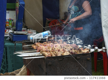 Fresh meat is fried on coals. Skewers of fresh meat roasting on the grill over charcoal 117411088