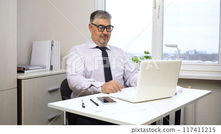 A man in a white shirt and tie works in the office 117411215