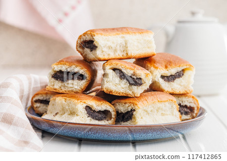 Sweet bun with poppy seed on plate on white table. Sweet bun with poppy seed on plate on white table. 117412865
