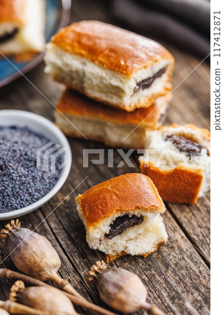 Sweet bun with poppy seed on wooden table. 117412871