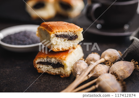 Sweet bun with poppy seed on black table. 117412874