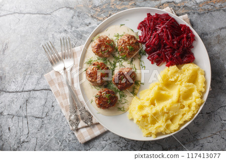 Small meatballs with creamy sauce served with mashed potatoes and beets close-up in a plate. Horizontal top view Small meatballs with creamy sauce served with mashed potatoes and beets close-up in a plate. Horizontal top view 117413077