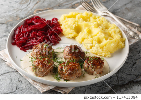 Tender meatballs served in a rich, creamy gravy with mashed potatoes and beet salad close-up in a plate. Horizontal Tender meatballs served in a rich, creamy gravy with mashed potatoes and beet salad close-up in a plate. Horizontal 117413084