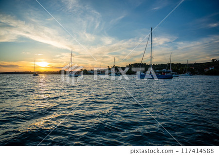 Yachts moored on buoys near the shore in the bay of Uvala Gradina near the town of Vela Luka on the island of Korcula at sunset lights in Croatia Yachts moored on buoys near the shore in the bay of Uvala Gradina near the town of Vela Luka on the island of Korcula at sunset lights in Croatia 117414588