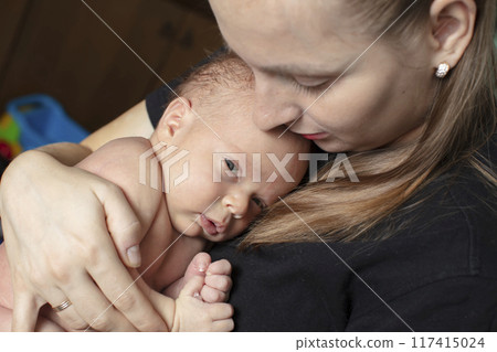 The newborn girl clung to her mother. Young woman with a baby. 117415024
