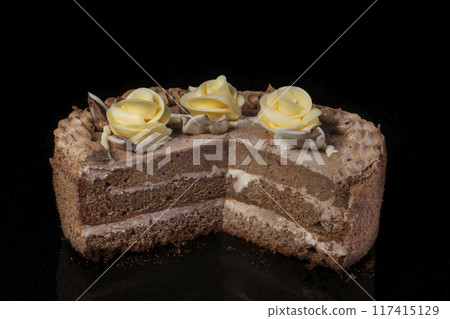 Chunk of chocolate cake decorated with oil cream on a black background 117415129