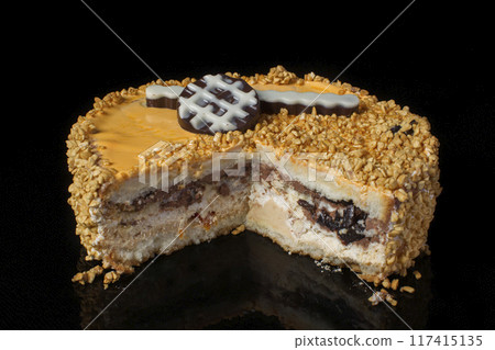 Piece of an ordinary cake covered with peanuts on a black background Piece of an ordinary cake covered with peanuts on a black background 117415135