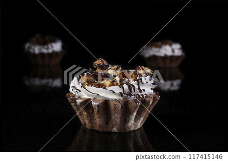 Chocolate cake with a cream and nuts on a dark black background 117415146