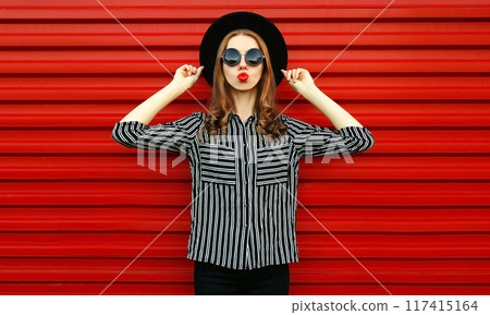 Portrait woman model wearing a black white striped shirt, round hat posing on red background Portrait woman model wearing a black white striped shirt, round hat posing on red background 117415164
