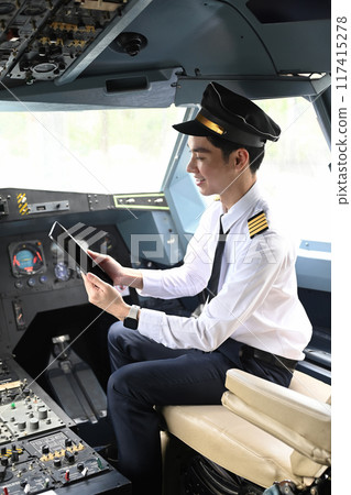 Pilot is sitting in the cockpit of an airplane and using digital tablet 117415278