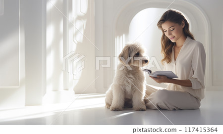 Woman reading a book to her dog in bright white room. 117415364