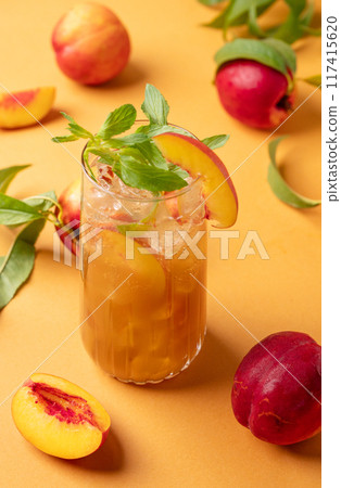 Peach ice and mint tea. Vegan homemade cold summer drink on an orange background with fresh fruits. 117415620