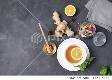 Flat lay herbal cup of tea with lemon, honey and mint on a dark background. Flat lay herbal cup of tea with lemon, honey and mint on a dark background. 117415635