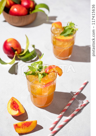 Two glasses with refreshing peach tea with ice and mint. Homemade cold summer drink Two glasses with refreshing peach tea with ice and mint. Homemade cold summer drink 117415636