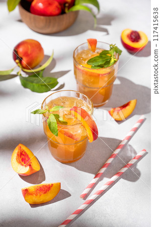 Two glasses with refreshing peach tea with ice and mint. Homemade cold summer drink Two glasses with refreshing peach tea with ice and mint. Homemade cold summer drink 117415638
