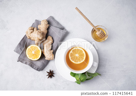 A cup of tea with lemon, honey, mint and ginger on a light background. A cup of tea with lemon, honey, mint and ginger on a light background. 117415641
