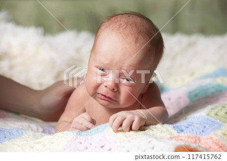 Newborn baby with funny face. Little baby crying. Baby holding her head 117415762