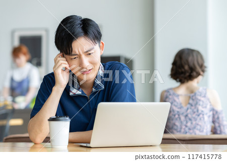 年輕人在咖啡館看電腦 117415778