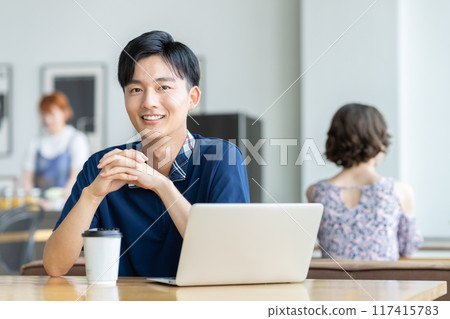 Young man looking at a laptop in a cafe 117415783