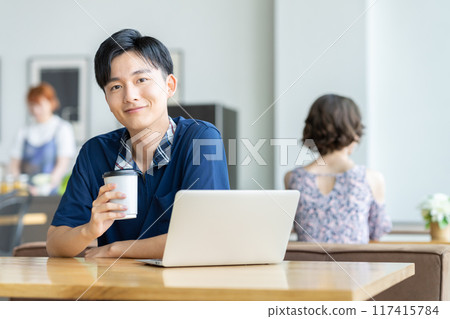 Young man looking at a laptop in a cafe 117415784