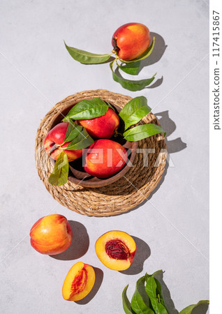 Juicy and sweet nectarines in a bowl on a light background with shadow. Healthy farm fruit concept. 117415867